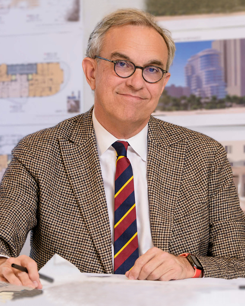 Portrait of Paul Whalen wearing a brown suit with a white shirt and multi-colored tie