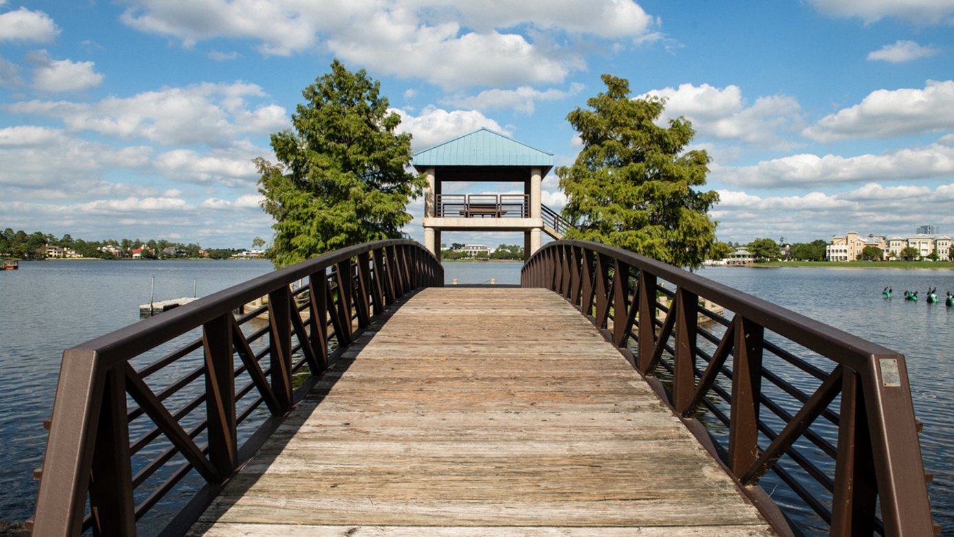 Front view of a wooden walkway with wooden guard rails and lake water on either side